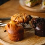 A wooden plate topped with muffins on top of a wooden table